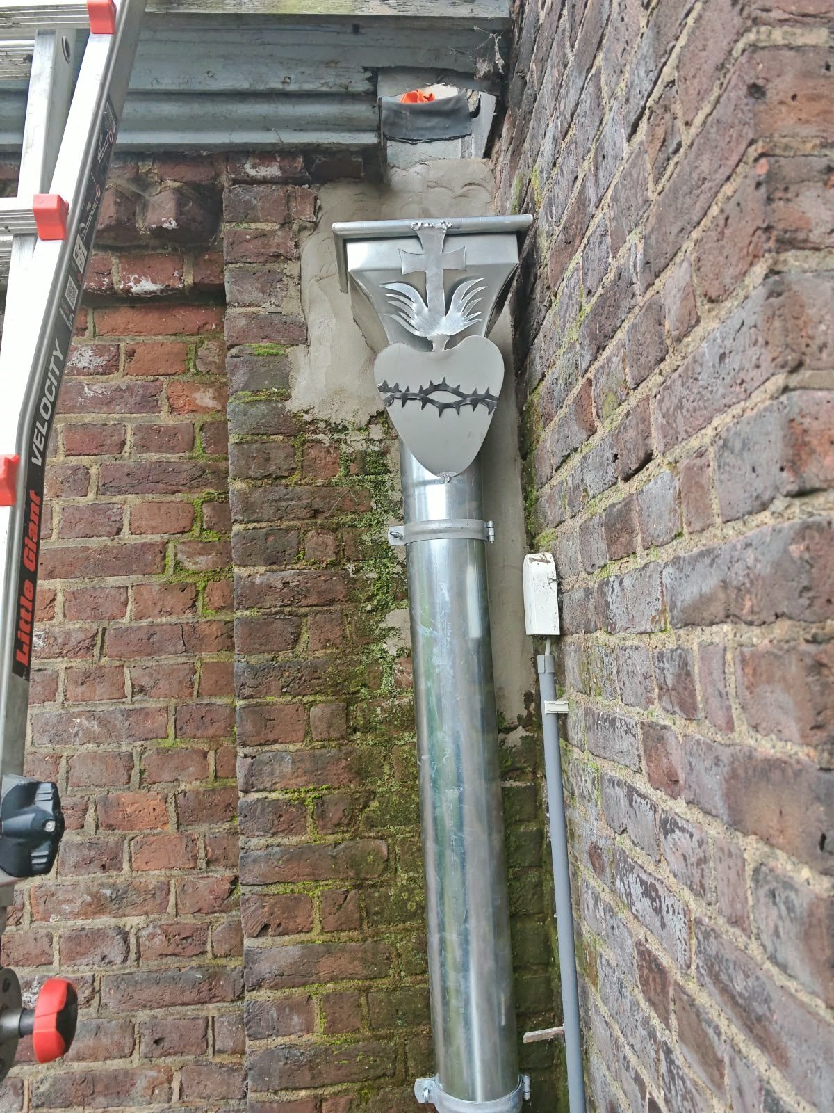 Descente d'eau pluviale avec tête ornementée posée sur une façade en brique par SkySafe Toitures
