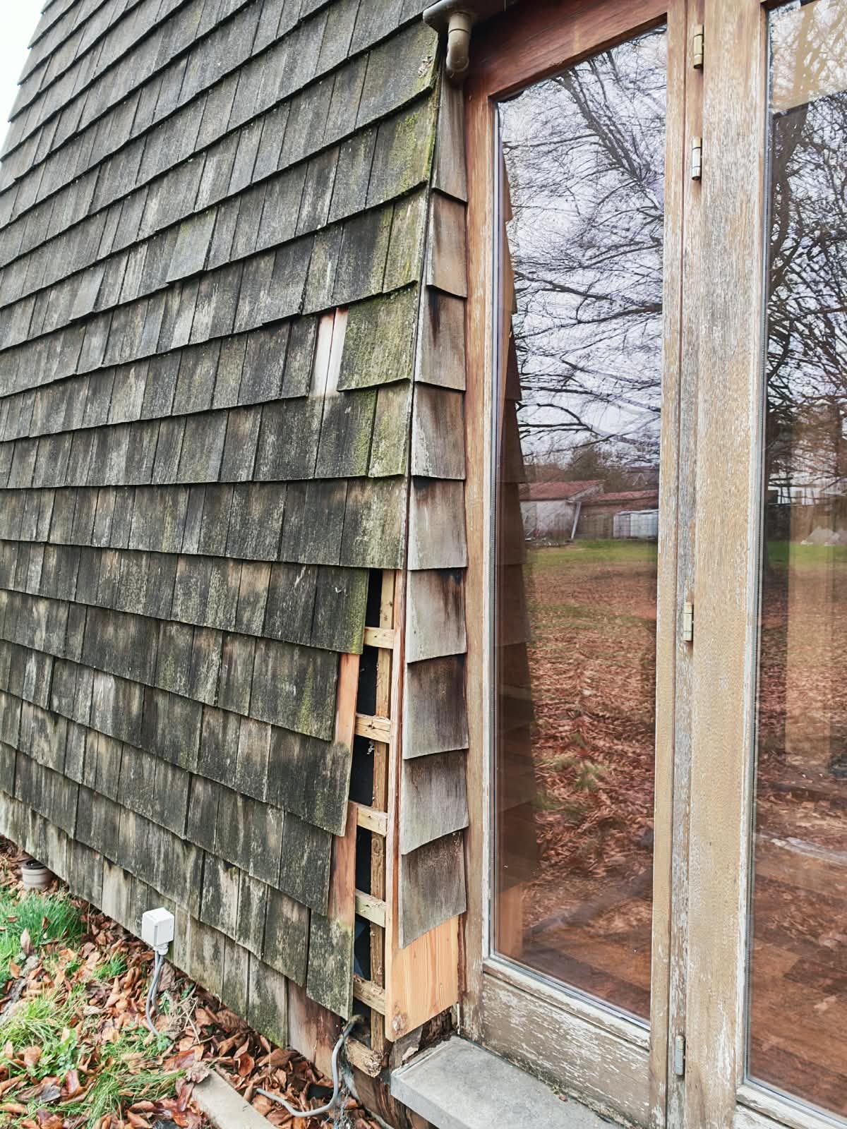 Façade en bardeaux de bois dégradés et envahis de mousse avant remplacement par SkySafe Toitures