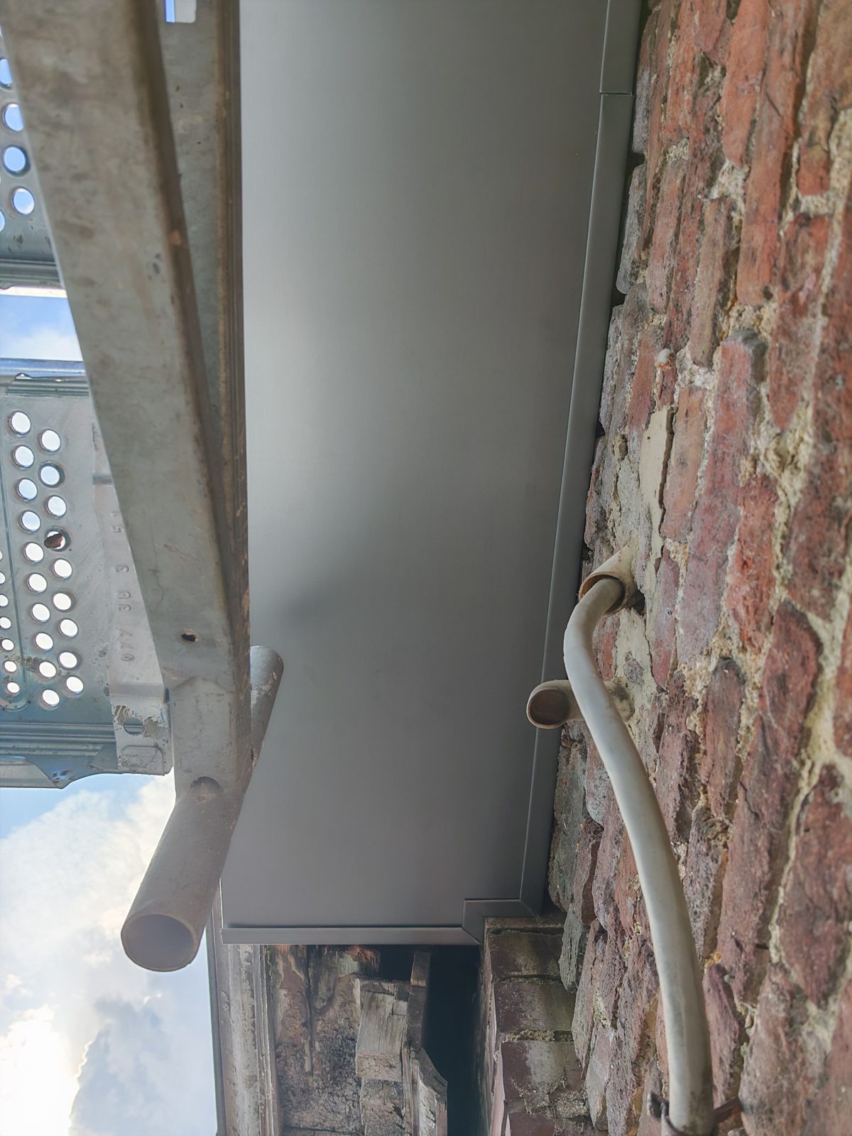 Détail d'une descente en zinc raccordée le long d'une façade, SkySafe Toitures